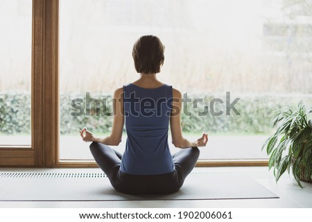 Young woman doing relaxation exercise, practicing yoga, girl meditating at home. Training, fitness, workout, meditation, yoga, self-care, relaxation, mindfulness, wellbeing, healthy lifestyle concept
