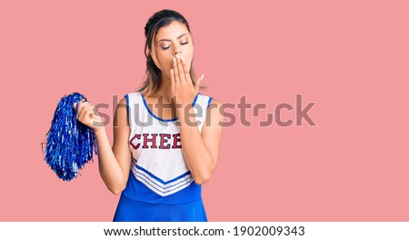 Young beautiful woman wearing cheerleader uniform bored yawning tired covering mouth with hand. restless and sleepiness. 