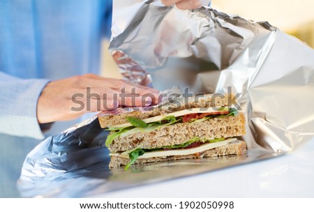 Close Up Of Woman Wrapping Sandwich In Non Reusable Aluminium Foil Royalty-Free Stock Photo #1902050998