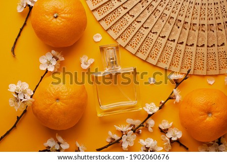 women's perfume, tangerines and sakura flowers. apricot blossom and apricots. concept. modern perfume photography. wooden fan