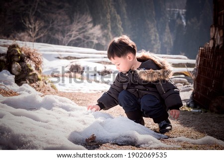 Cute Asian child playing on snow in japan. The boys was playing in the garden. With a smile of happiness. Soft focus.
