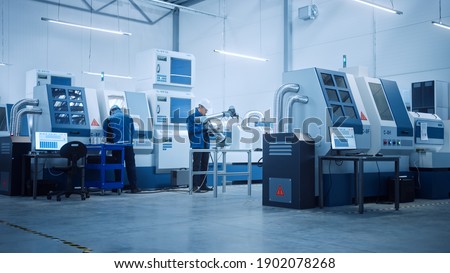 Modern Factory with Professional Workers, Engineers, Managers Working on Production Line, Workshop Management, Optimization. Industrial Facility: Equipped with CNC Machinery and robot arm Technology