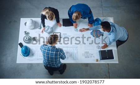 Team of Industrial Engineers Lean on Office Table, Analyze Machinery Blueprints, Architectural Problem Solving, Consult Project on Tablet Computer, Inspect Metal Component. Flat Lay Top Down View Royalty-Free Stock Photo #1902078577