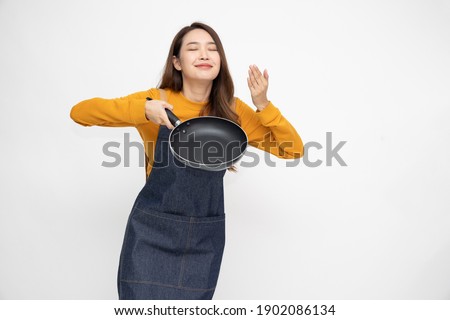 Young Asian woman housewife wearing kitchen apron cooking and holding pan isolated on white background Royalty-Free Stock Photo #1902086134
