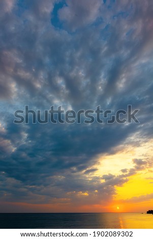 dynamic cloudscape in summer at sunrise. dark clouds on the sky in yellow and pink morning light. dramatic weather condition, picturesque scenery above the sea