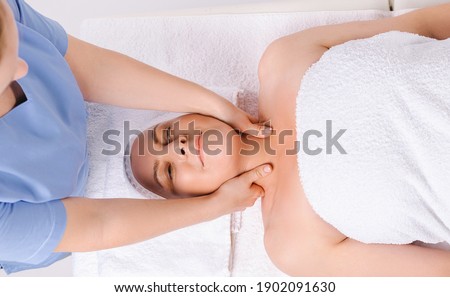 The master masseur is giving a relaxing head and neck massage to an older woman wrapped in a white towel.