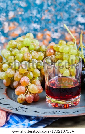 Bunch of grapes and a glass of juice on blue background. High quality photo