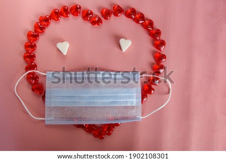 Heart emoticon with medical mask on a pink background. The concept of silence, do not go forward, protection from the virus.