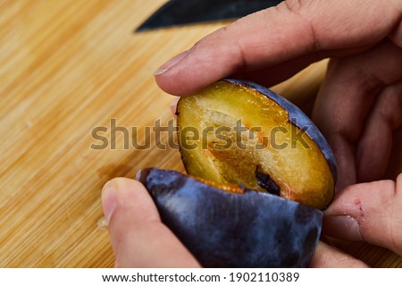 Holding fresh plum on wooden board. High quality photo