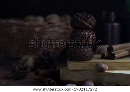 small chocolate cakes with droplets of chocolate stand on top of each other. cakes stand on a wooden board