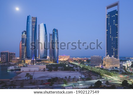 A unique and different perspective of skyscraper towers and cityscape skyline of Abu Dhabi, UAE at night under moonlight.