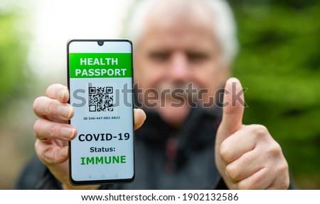 Senior man showing a health passport on a mobile phone, which indicates a vaccination against covid-19. Royalty-Free Stock Photo #1902132586