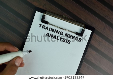 Training Needs Analysis write on a paperwork isolated on Wooden Table.