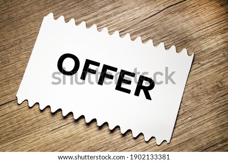 The offer is written on a white sheet that lies on a wooden texture table.