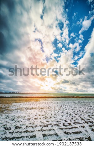 field with winter covered with snow  against the sky with clouds, rural winter landscape, blurred image