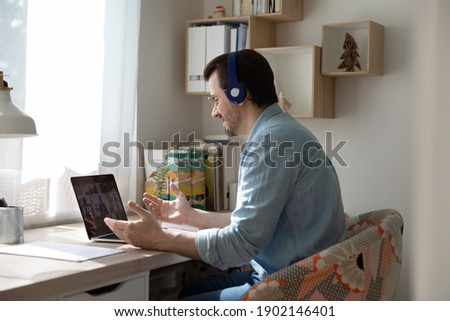 Corporate meeting online. Confident businessman sit by laptop in headphones negotiating with partners online from home. Male remote employee discuss work problems with colleagues via video conference Royalty-Free Stock Photo #1902146401