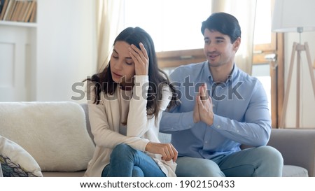 Husband asking forgiveness, making peace with offended annoyed wife after quarrel or cheating, young woman ignoring man, not talking, family crisis, relationship problem, break up and divorce Royalty-Free Stock Photo #1902150433