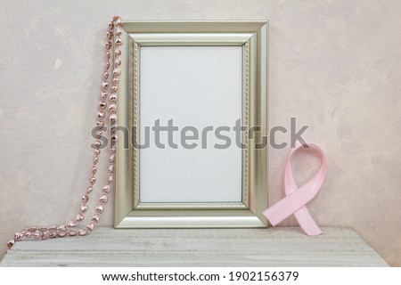Silver Frame Mockup with pink cancer ribbon against pink textured wall for copy space or artwork