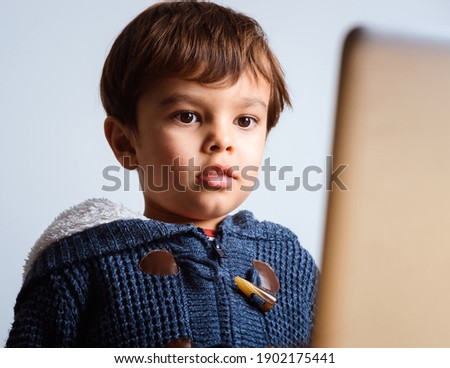 Cute little boy watching cartoon on laptop screen