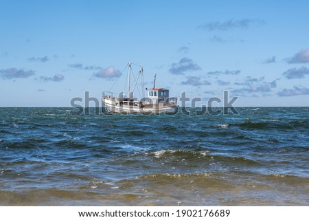 there are waves in the sea and there is a small fishing boat in the distance