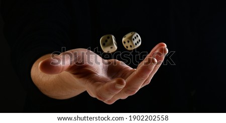 Female hand throwing two white dice in the air on black background. Game with dice, Hazard, Cho-Han Bakuchi, Under-Over 7, Mexico, Shut the Box. Gambling luck concept: bet, risk, have luck, win. lucky Royalty-Free Stock Photo #1902202558