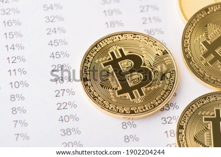 Above top close up view photo of golden shiny bitcoin laying on numbers with percentage ont he backgroundAbove top close up view photo of golden shiny bitcoin laying on numbers with percentage 