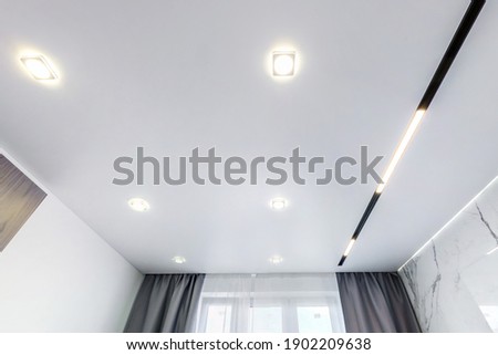 suspended ceiling with halogen spots lamps and drywall construction in empty room in apartment or house. Stretch ceiling white and complex shape. Royalty-Free Stock Photo #1902209638