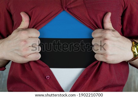 Young sport fan opening his shirt and showing the flag Estonia