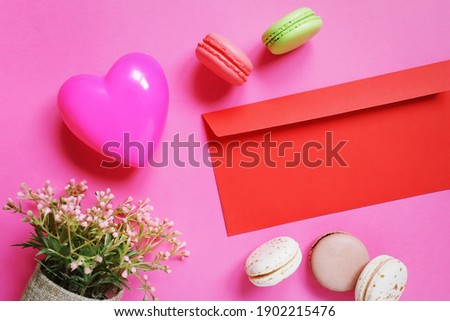 Heart shaped box, red envelope, flowers and macarons. French almond cookies macaroons and 14 february decoration. Valentine's Day flat lay composition photography. Romantic background