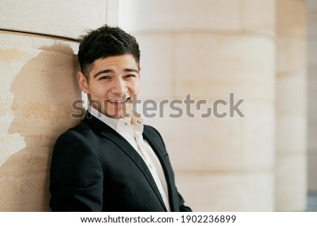 portrait of a man of European appearance looking at the camera smiling. He is dressed in a black business suit and a white shirt. student manager at the bank on a break. copy space