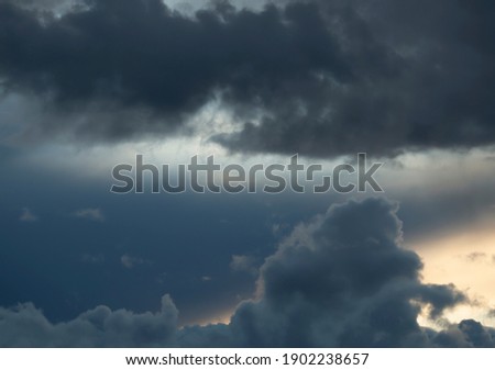 Moody photo of rainclouds with sunlight behing the clouds Royalty-Free Stock Photo #1902238657