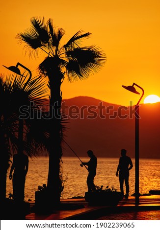 Fisher man with fishing rod on the beach at sunset