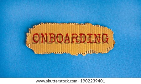 Onboarding symbol. The concept word 'onboarding' on the piece of cardboard. Beautiful blue background, copy space. Business and onboarding concept.