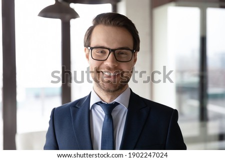 Head shot portrait smiling confident businessman wearing glasses and suit standing in modern office, executive manager company owner employee looking at camera, mentor coach posing for photo Royalty-Free Stock Photo #1902247024