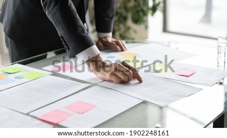 Close up businessman working with documents, reading notes on colorful stickers, employee executive analyzing financial statistics, developing corporate project strategy analyzing statistics Royalty-Free Stock Photo #1902248161