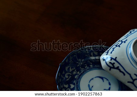picture plate. 
This is a very fine example of Japanese traditional. 
lay out vintage ceramic “ imari ware ”. 

This antique walnut table is made in England. 
wooden background. soft focus image.