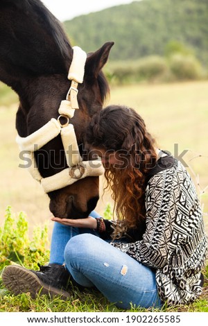 Young beautiful Woman staying with her horse at sunset, spring outdoors scene. Two horses. Stalion. 