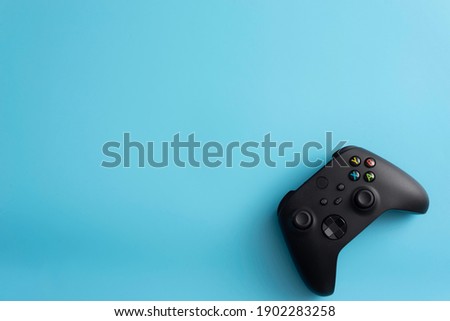new black video game controller, video game controller on light blue background 