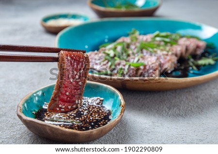 Beef tataki with sauce and sesame on blue plate. Japanese food Royalty-Free Stock Photo #1902290809