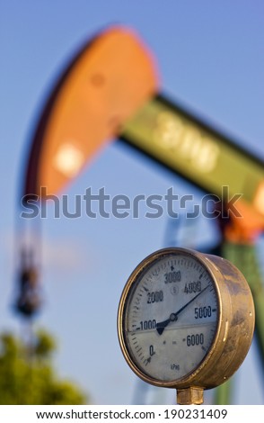 A pressure gauge and an oil pump at sunset