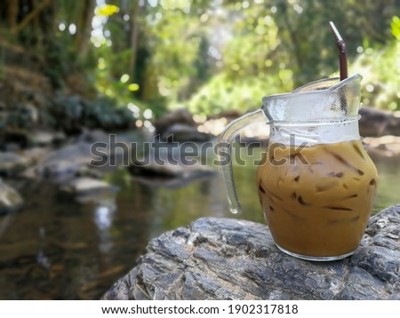 Background of brown coffee with ice on good texture rock beside stream in the forest . Peaceful and relax time