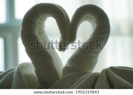 swan towels on the bed. Love Sign using one large and two small towels. Make it as a Valentine's Day display for yourself and your loved ones. Romantic Honeymoon concept.
