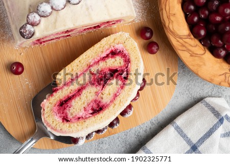Homemade biscuit sweet roll with cranberries and cream on gray table, top view, flat lay