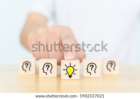 Concept creative idea and innovation. Hand choose wooden cube block with head human symbol and light bulb icon Royalty-Free Stock Photo #1902337021