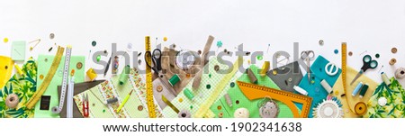Spring sewing and home needlework. Panoramic top view on green and yellow pieces of fabric, and sewing accessories on white background. Flat lay, copy space, closeup, banner, mock up Royalty-Free Stock Photo #1902341638