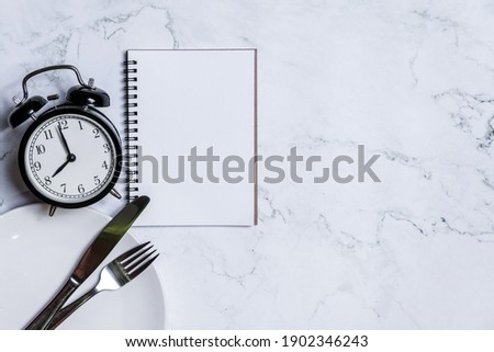 Food clock with notebook. Healthy food concept on white background