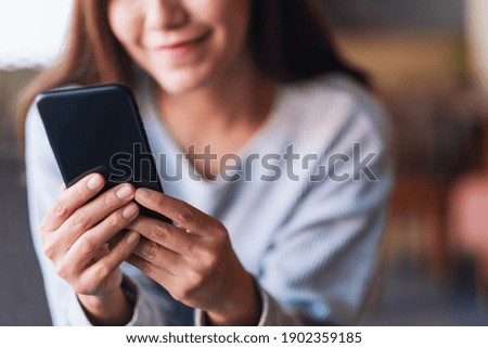 Closeup image of a beautiful young asian woman holding and using mobile phone