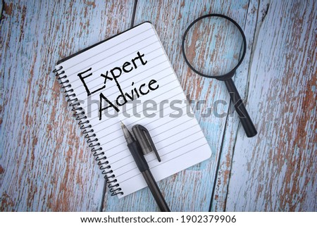 Selective focus image of magnifying glass with a pen on a wooden background with Expert Advice wording . Vintage style. Business and economy concept.