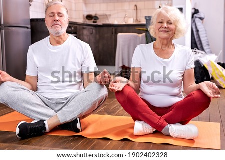 mature couple sit on the floor meditating in lotus pose, engaged in yoga, keep calm with eyes closed