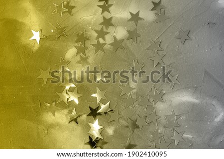 Gold confetti stars on a grey christmas background.